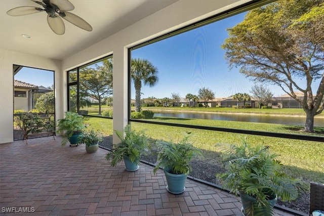 unfurnished sunroom with ceiling fan and a water view