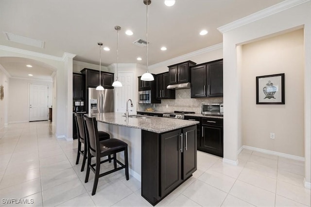 kitchen featuring visible vents, a sink, under cabinet range hood, appliances with stainless steel finishes, and backsplash