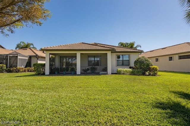 back of house with a tiled roof, a lawn, and stucco siding