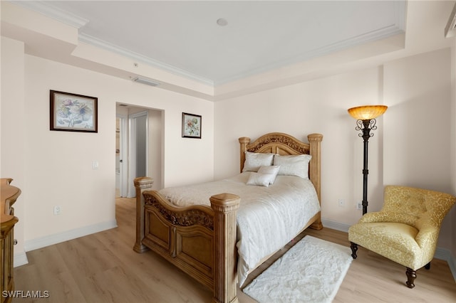 bedroom featuring baseboards, light wood finished floors, visible vents, and crown molding