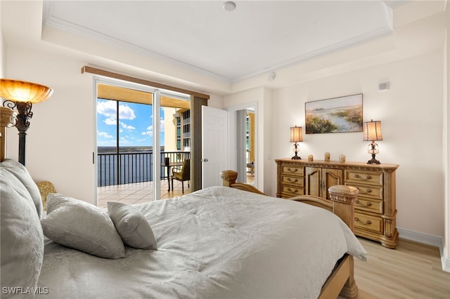 bedroom featuring light wood-style floors, access to outside, ornamental molding, and a tray ceiling