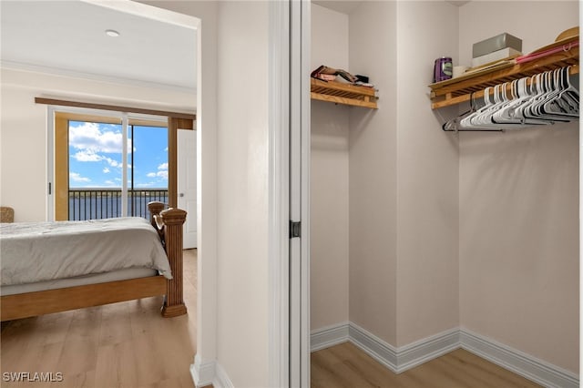 bedroom featuring access to exterior, baseboards, and wood finished floors
