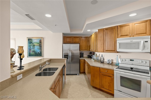 kitchen with a tray ceiling, stainless steel appliances, recessed lighting, visible vents, and a sink