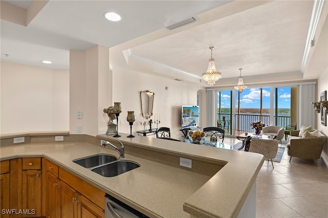 kitchen with visible vents, brown cabinetry, a raised ceiling, a peninsula, and a sink