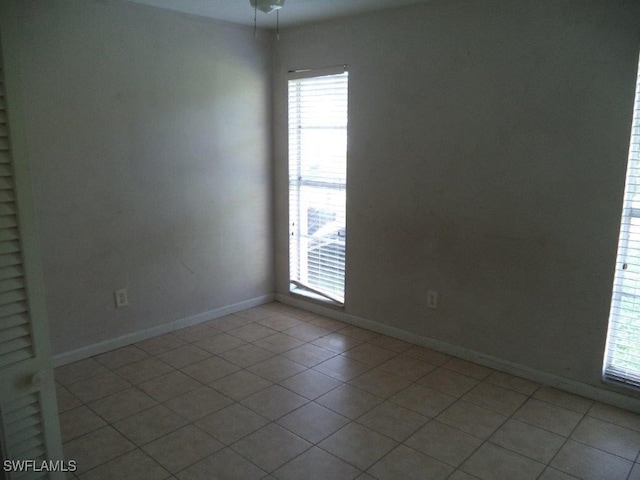 spare room featuring light tile patterned flooring and baseboards