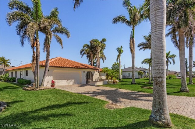 5305 SW 25th Ct, Cape Coral, FL 33914 - mediterranean / spanish-style house with an attached garage, stucco siding, a tiled roof, driveway, and a front yard