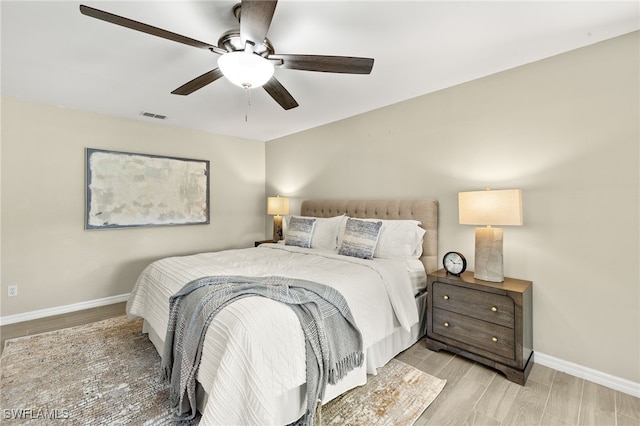 bedroom with visible vents, light wood-style flooring, a ceiling fan, and baseboards