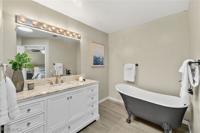 ensuite bathroom with vanity, wood finished floors, baseboards, a soaking tub, and ensuite bath