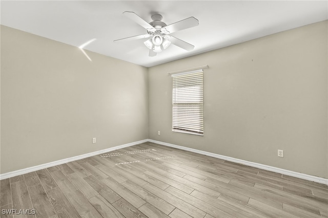 spare room featuring baseboards, light wood-style floors, and a ceiling fan