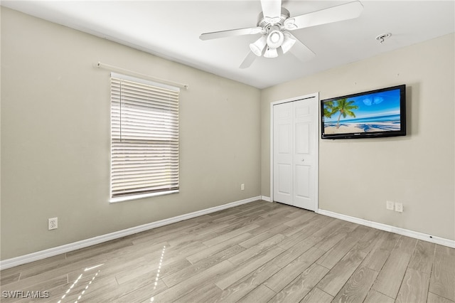 unfurnished bedroom with a ceiling fan, wood finished floors, baseboards, and a closet