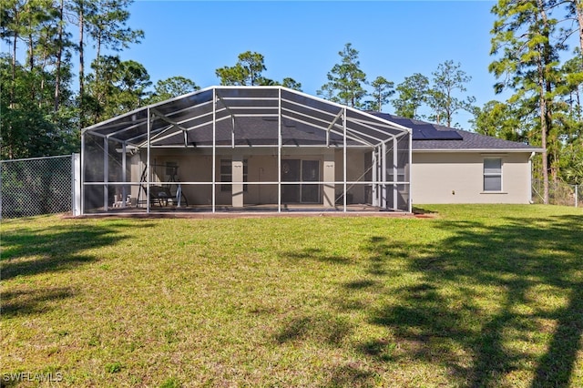 rear view of house featuring a lanai, stucco siding, a yard, and fence