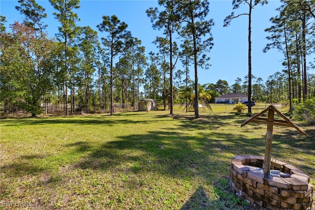 view of yard featuring a storage shed, an outbuilding, fence, and an outdoor fire pit