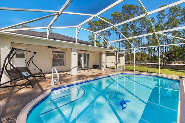 pool with glass enclosure, a patio, and a ceiling fan