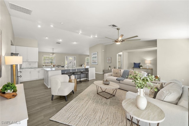 living area featuring visible vents, ceiling fan, vaulted ceiling, and light wood-style flooring