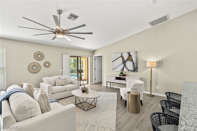 living area with lofted ceiling, a ceiling fan, visible vents, and light wood finished floors