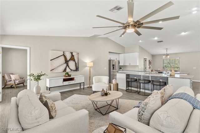 living room with vaulted ceiling, a ceiling fan, visible vents, and light wood-type flooring