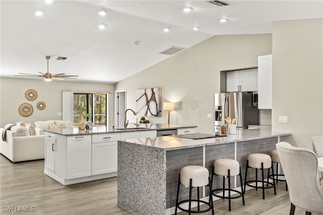 kitchen with visible vents, a peninsula, a sink, appliances with stainless steel finishes, and white cabinetry