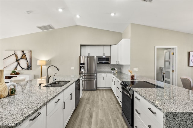 814 Louis Ave, Lehigh Acres, FL 33972 - kitchen featuring white cabinetry, a sink, appliances with stainless steel finishes, vaulted ceiling, and a peninsula