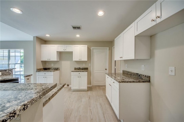 kitchen with stone countertops, recessed lighting, white cabinets, and visible vents