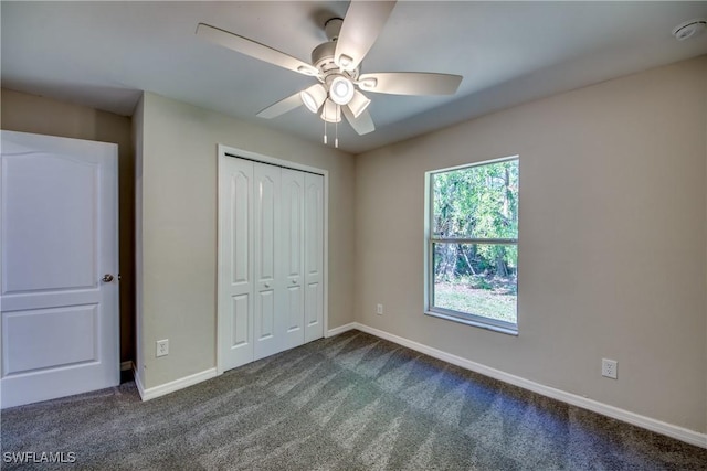 unfurnished bedroom featuring baseboards, dark colored carpet, and a closet