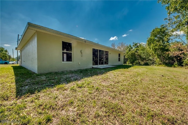 back of property with a lawn and stucco siding