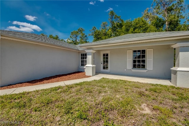 entrance to property with a yard and stucco siding