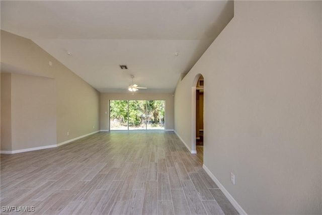 unfurnished room featuring visible vents, arched walkways, a ceiling fan, vaulted ceiling, and light wood-type flooring