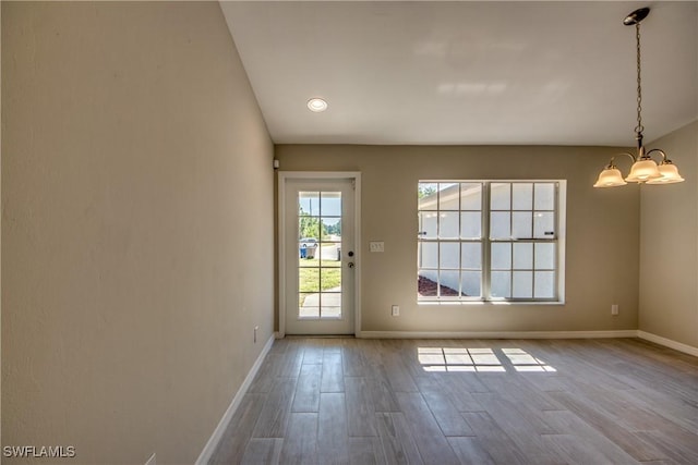 doorway to outside featuring baseboards, a notable chandelier, and wood finished floors