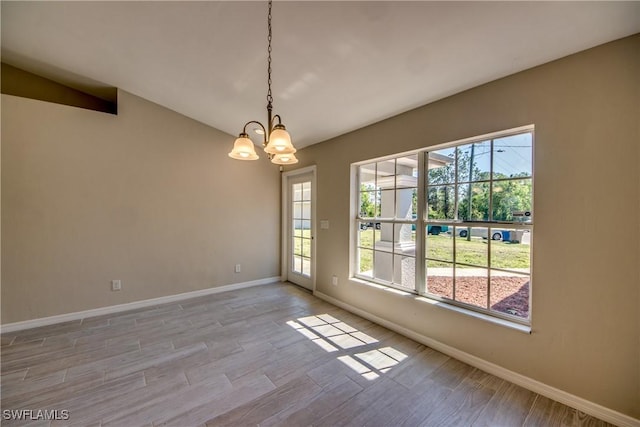 spare room with light wood-style floors, a chandelier, and baseboards