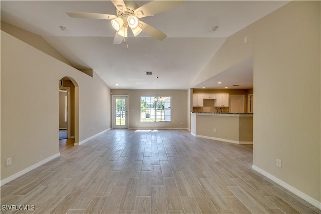 unfurnished living room with light wood-style floors, baseboards, arched walkways, and ceiling fan