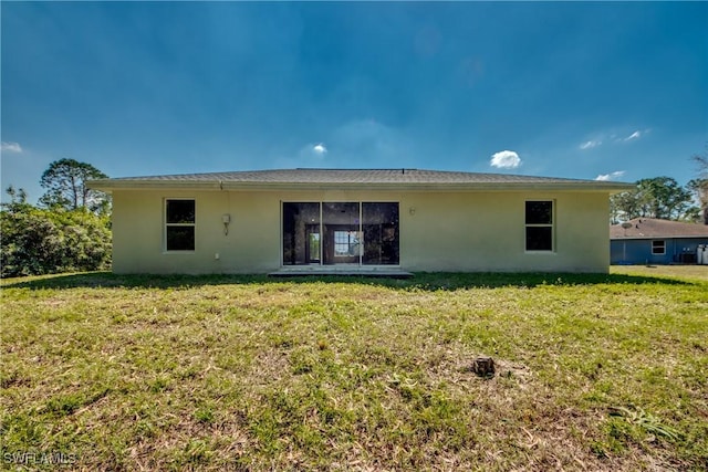 rear view of property with a yard and stucco siding