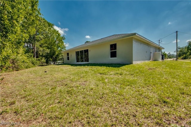 rear view of house featuring a yard and stucco siding