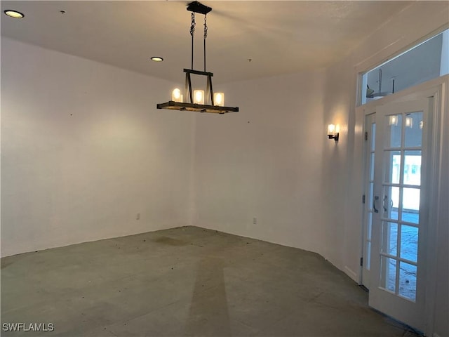 unfurnished dining area featuring concrete flooring and a chandelier