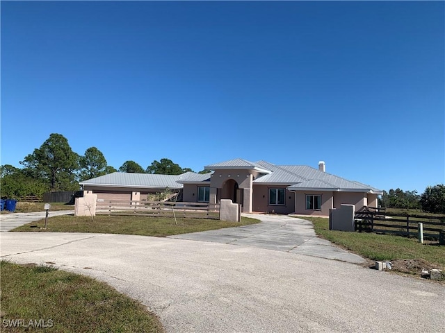 view of front of property featuring metal roof, fence, stucco siding, a front lawn, and a standing seam roof