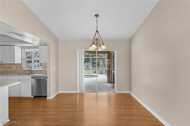 unfurnished dining area with light wood finished floors, baseboards, and a sink