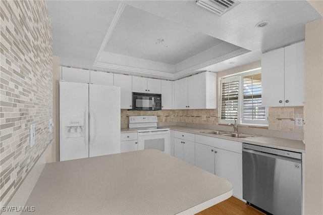 kitchen featuring white appliances, visible vents, a raised ceiling, white cabinetry, and a sink