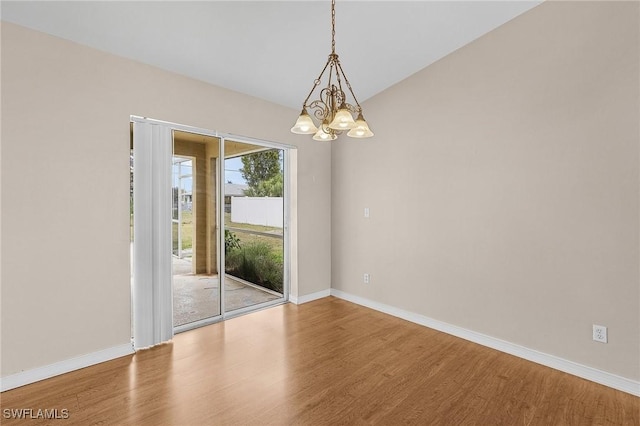 unfurnished room featuring an inviting chandelier, baseboards, vaulted ceiling, and wood finished floors