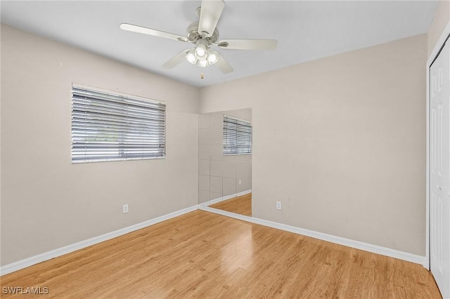 unfurnished room with ceiling fan, wood finished floors, and baseboards