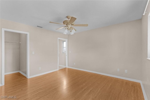 unfurnished bedroom with visible vents, baseboards, light wood-style flooring, a spacious closet, and a closet