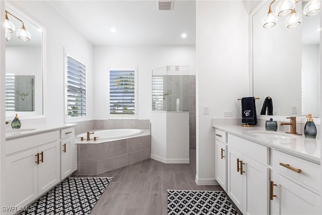 full bath with two vanities, visible vents, a walk in shower, and a sink