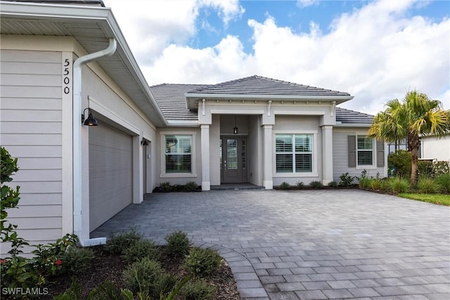 entrance to property featuring a garage and decorative driveway