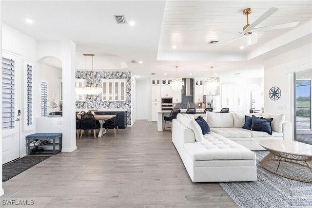 living room with wood finished floors, a raised ceiling, visible vents, and recessed lighting