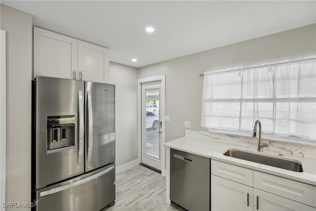 kitchen with white cabinetry, appliances with stainless steel finishes, light countertops, and a sink