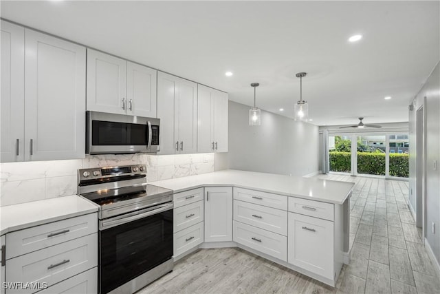 kitchen with a peninsula, tasteful backsplash, white cabinetry, and stainless steel appliances