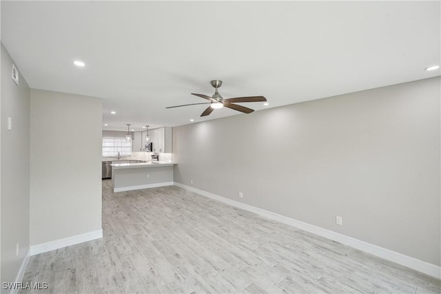 unfurnished living room featuring a ceiling fan, recessed lighting, light wood-style flooring, and baseboards