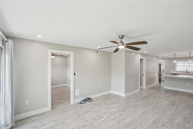 unfurnished living room with a ceiling fan, recessed lighting, light wood-style flooring, and baseboards