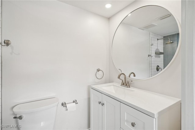 bathroom featuring visible vents, a tile shower, vanity, and toilet