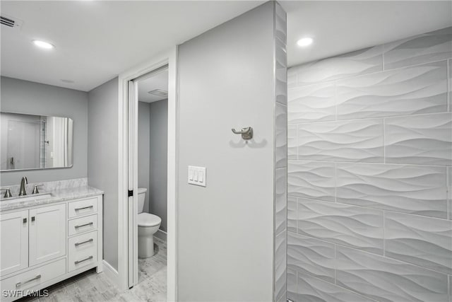 full bathroom with toilet, wood finished floors, visible vents, vanity, and tiled shower