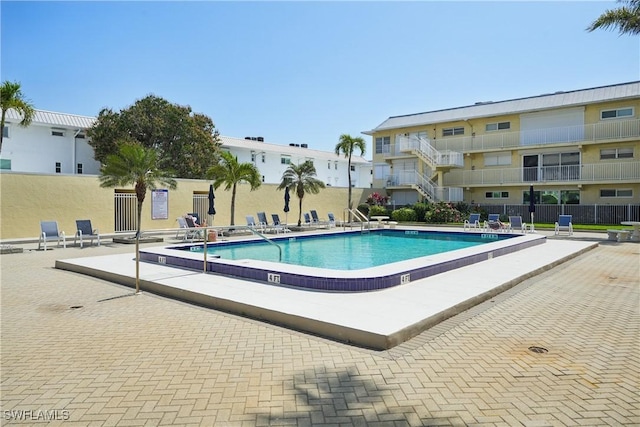 community pool with a patio area and fence