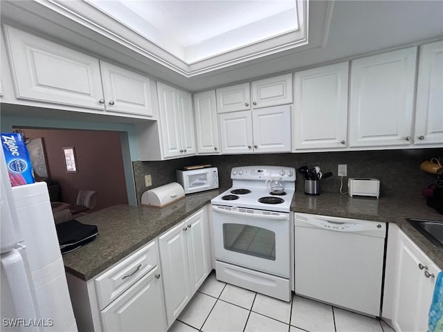 kitchen with white appliances, white cabinets, a peninsula, and light tile patterned floors